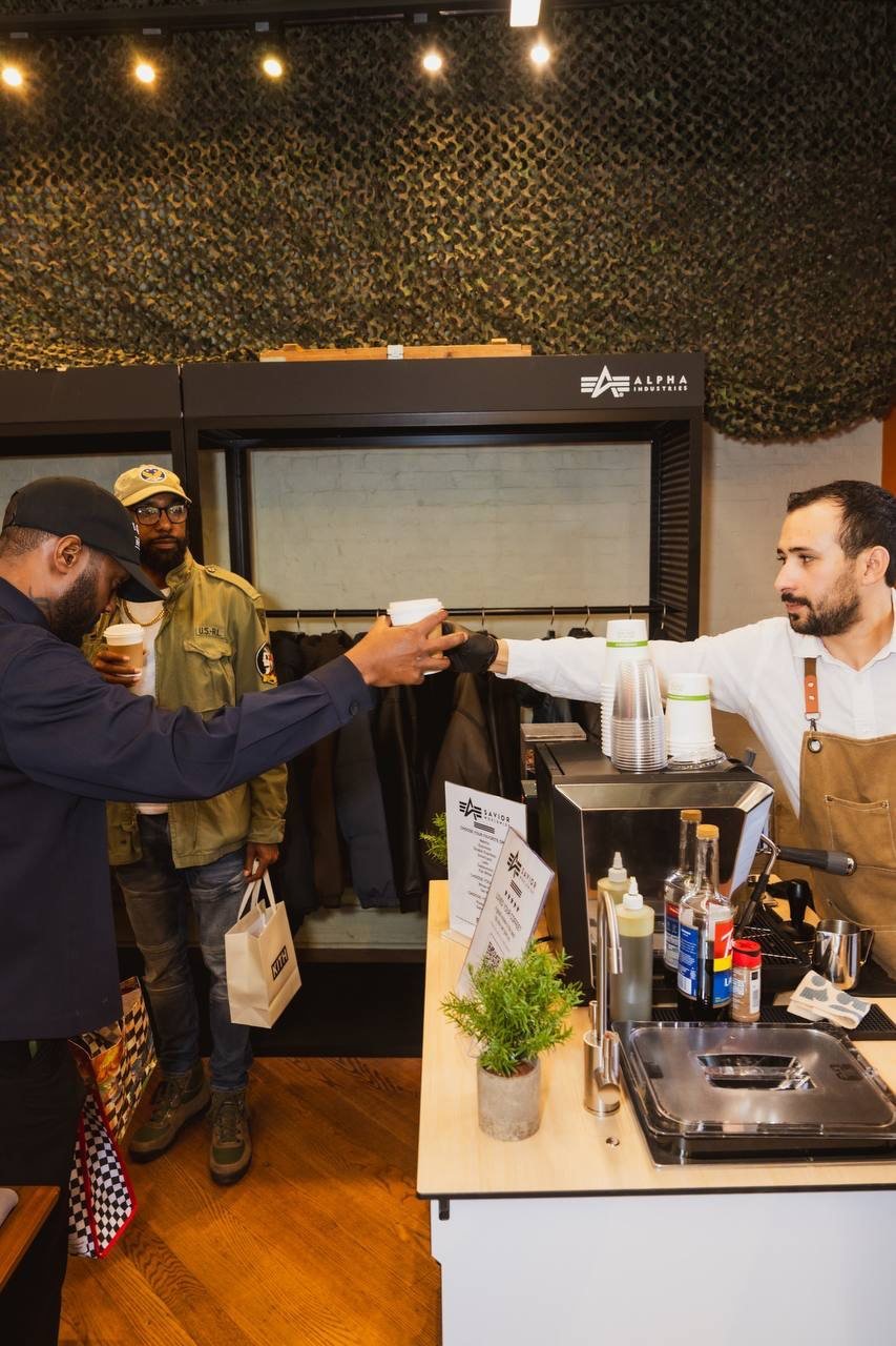 Barista handing a coffee across the Fes Coffee cart to a guest at a retail store event