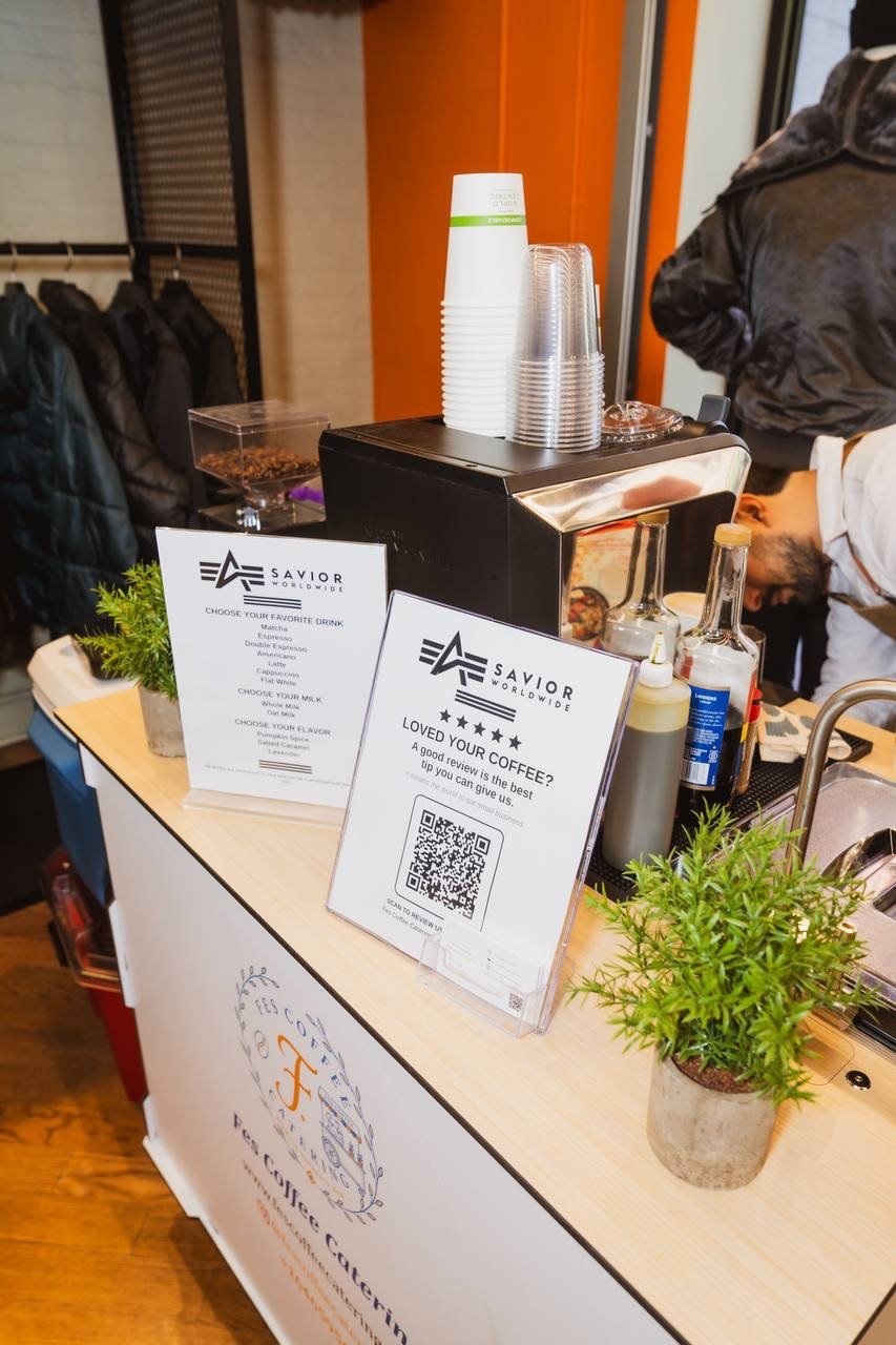 Close-up of the Fes Coffee cart counter with printed menu signs, cups and a small plant
