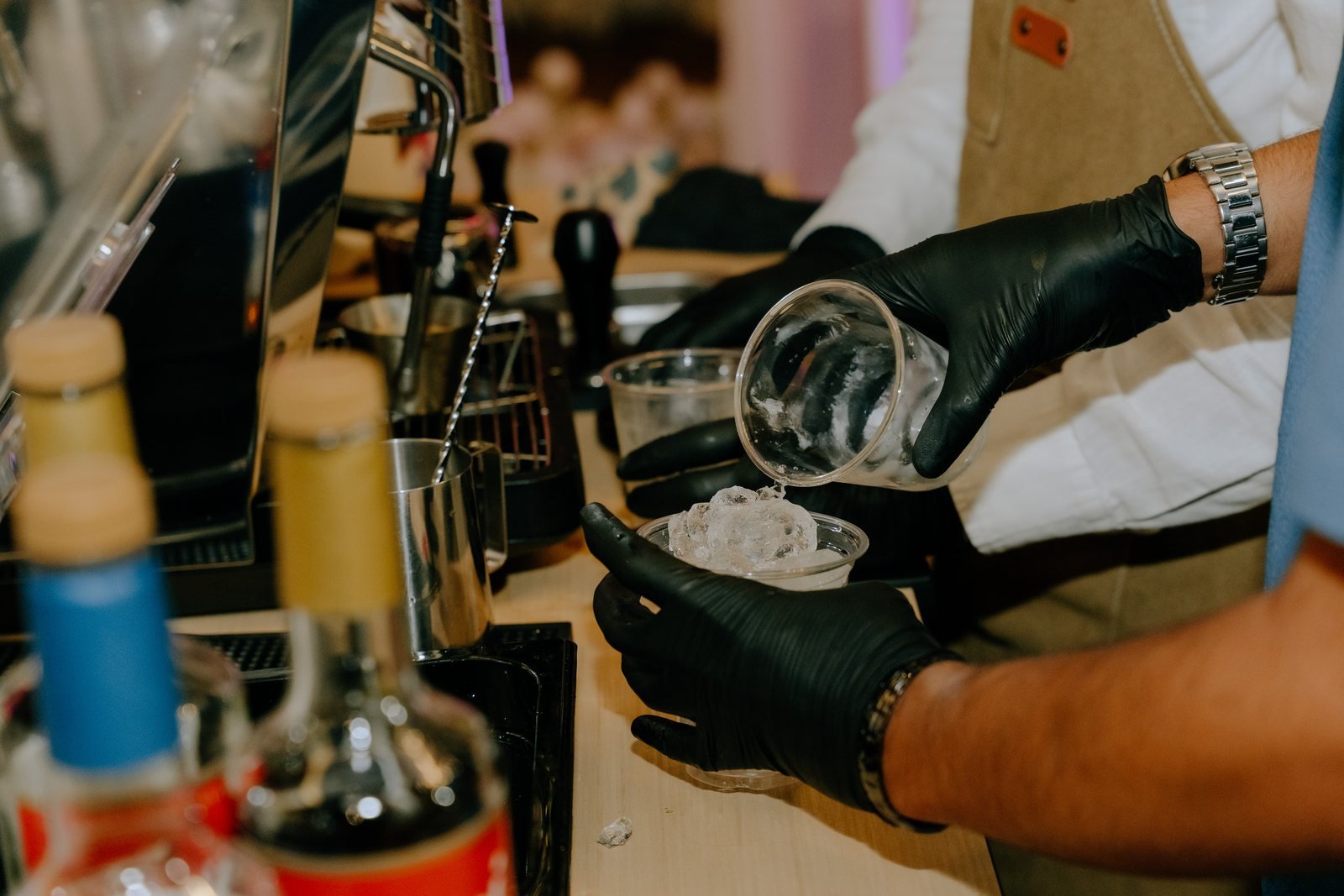 Barista pouring a drink over ice into a glass at the Fes Coffee cart, syrup bottles in front