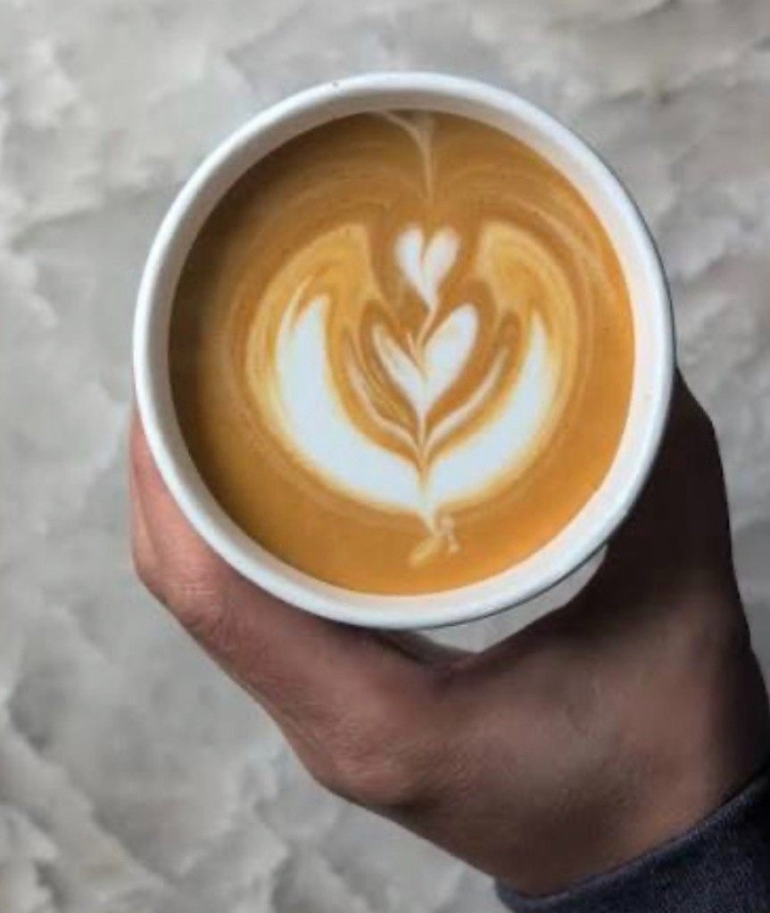 Latte art heart design in a Fes Coffee paper cup