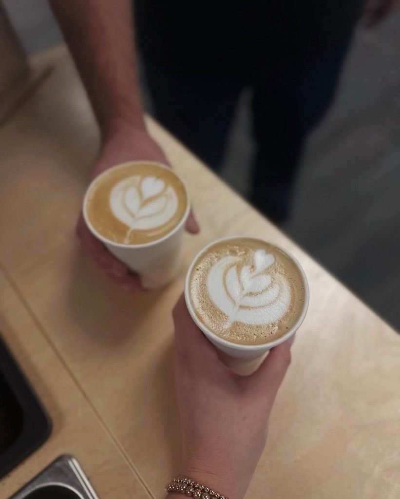 Two hot lattes with latte art held over the cart